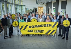 Ein gemeinsames Gruppenfoto mit passenden Werbematerialien zur Kampagne "Kommunen am Limit"